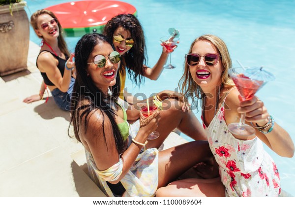 夏休み中の多人種の女性の友達が プールでリラックスし カクテルを飲む 飲み物を飲みながらプールサイドパーティーを楽しむ女の子 の写真素材 今すぐ編集