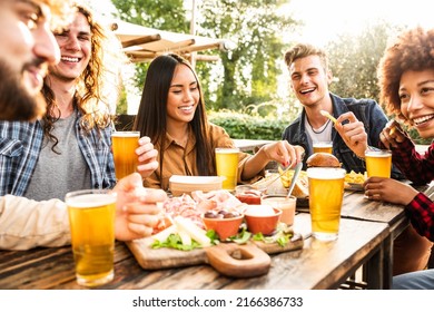 Group Of Multiracial Friends Having Backyard Dinner Party Together - Diverse Young People Sitting At Bar Table Toasting Beer Glasses In Brewery Pub Garden - Happy Hour, Lunch Break And Youth Concept