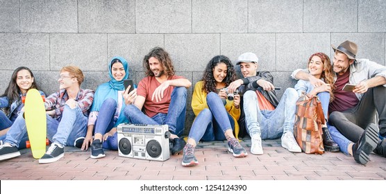 Group of multiracial friends having fun outdoor - Millennial young people using mobile phones taking photo and listening music with vintage stereo - Generation z, social and youth lifestyle concept