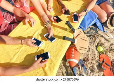 Group of multiracial friends having fun together with smartphone - Closeup of mixed hands social networking with mobile smart phone in sunny day - Technology concept in summer beach everyday lifestyle
