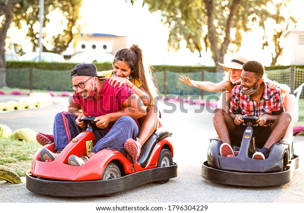 Group of\
multiracial friends having fun with go kart  - Young people with\
face mask on smiling and cheerful at mini car racing - Couples\
outside in double date - New\
lifestyle