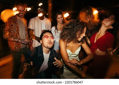 A group of multiracial friends is having a great time at the rooftop nightclub. They are dancing and clubbing at the night open-air party. - Powered by Shutterstock