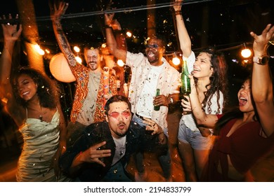 A group of multiracial friends is at the open-air rooftop club at night and having a good time. They are dancing, drinking beer, and celebrating summer. There is confetti everywhere. - Powered by Shutterstock