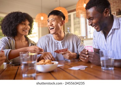 Group Of Multi-Racial Friends Sitting Around Table Playing Game Of Cards At Home Together - Powered by Shutterstock