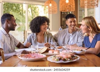 Group Of Multi-Racial Friends Sitting Around Table Enjoying Meal At Home Together - Powered by Shutterstock