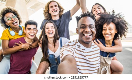 Group multiracial friends taking selfie picture with mobile smartphone outside - Happy young with hands up laughing at camera - Youth concept with guys and girls having fun walking on city street