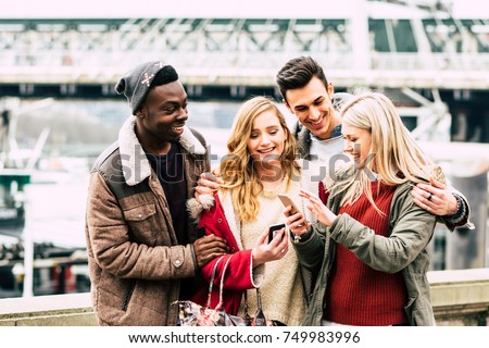Group of multiracial friends using mobile smart phone in the city during best friends meeting - Young hipster people addicted by smartphone on social network community by posting - Technology concept 