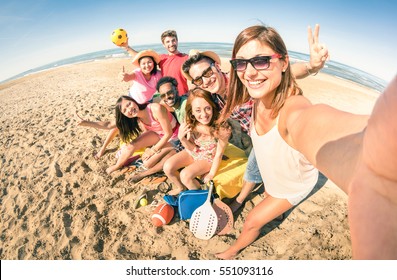 Group of multiracial happy friends taking selfie and having fun with beach sport games - Summer joy concept and multi ethnic friendship - Sunny afternoon color tones with focus on girl holding camera