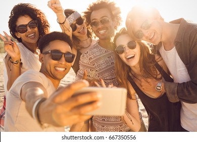 Group of multiracial happy friends taking selfie and having fun on a beach - Powered by Shutterstock