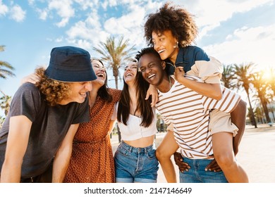 Group of multiracial happy young friends having fun together enjoying summer vacation on the beach - Focus on african couple - Powered by Shutterstock