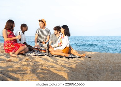 Group of multiracial having fun at the beach, talking, playing bongos and drinking beer together. Copy space.
