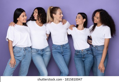 Group Of Multiracial Ladies Embracing Posing Together Standing In Studio Over Purple Background, Smiling Each Other. Multicultural Beauty Diversity And Female Friendship Concept