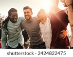 Group of multiracial men laughing together outdoors - Expression of joy and friendship among diverse friends.