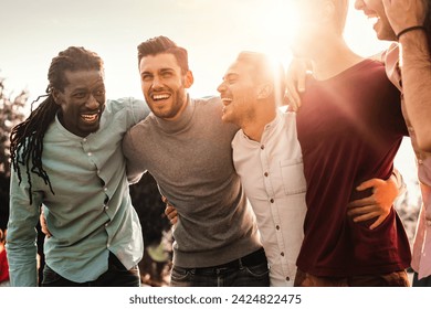 Group of multiracial men laughing together outdoors - Expression of joy and friendship among diverse friends. - Powered by Shutterstock