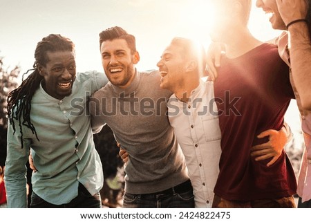Group of multiracial men laughing together outdoors - Expression of joy and friendship among diverse friends.