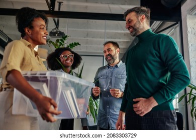 Group Of Multiracial People In The Office Talking With Their Colleague Who Return To Work And Carrying Plastic Box With Office Supplies