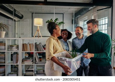 Group Of Multiracial People In The Office Talking With Their Colleague Who Return To Work And Carrying Plastic Box With Office Supplies