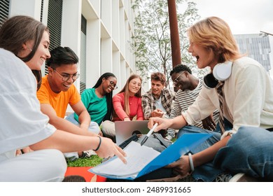 Group of multiracial students doing homework together, sitting on the university campus lawn. Teenagers sharing notes to study for their high school exam. Young people talking and learning the lesson - Powered by Shutterstock