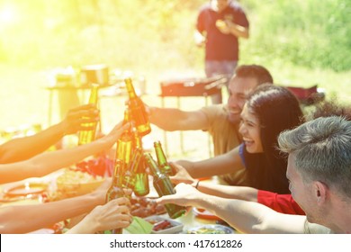 Group of multiracial students having barbecue on a sunny day - Young cheerful people cheering with beer bottles on summer time - Concept about good and positive mood with friends - Focus on blonde guy - Powered by Shutterstock