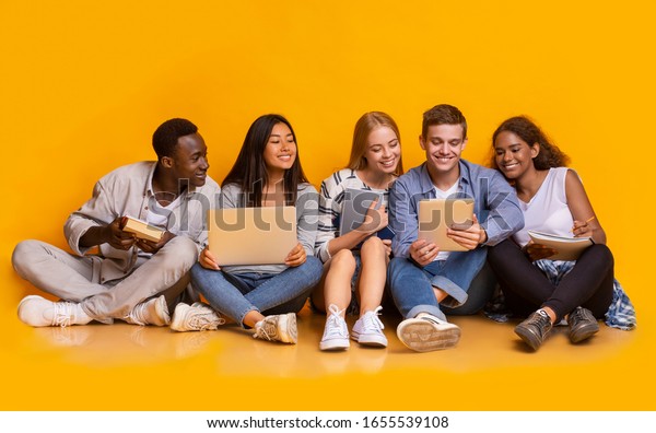 Group of multiracial students studying for university exams, sitting on