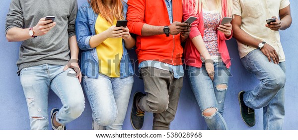 Group of multiracial students watching smart\
mobile phones in university break - Young people addiction to new\
technology trends - Alienation moment for new generation problem -\
Focus on center hands 