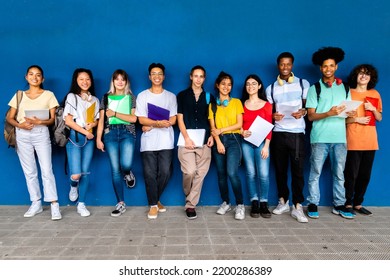 Group Of Multiracial Teenage High School Students Looking At Camera Standing On Blue Background. Back To School.