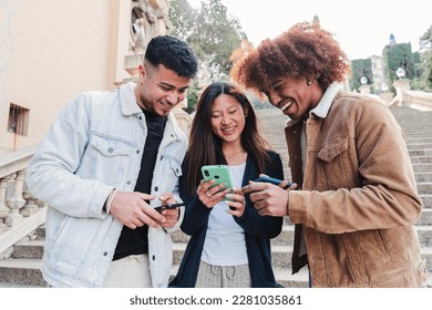 Group of multiracial teenagers watching funny videos on a social media app using a cellphone. Three young friends sharing content and having fun together with a smartphone.. happy people with phone - Powered by Shutterstock