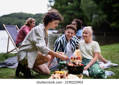 Group Of Multiracial Young Friends Camping Near Lake And And Having Barbecue Together.