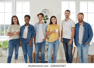 Group of multiracial young people standing in row posing for photo. Happy male and female friends or international diverse students wearing casual clothes standing together indoors - Shutterstock ID 2284463367