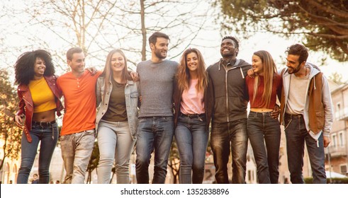 Group of multiracial young people students arms around shoulders together in a park