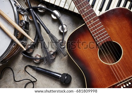 a group of musical instruments including a guitar, drum, keyboard, tambourine.