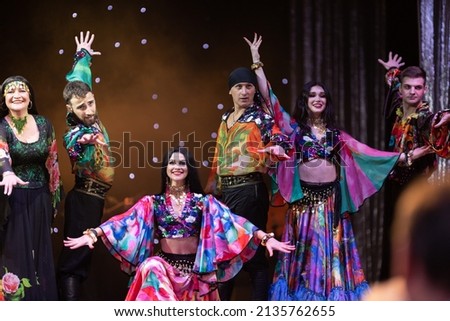 A group of musicians, singers and dancers in gypsy costumes perform on stage.