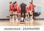 A group of nice teen sport in gymnase play volleyball, focus on ball in front