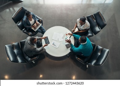 Group Of North African Business People Sitting And Discussing Statistics During A Sit Down Meeting Taking From Above