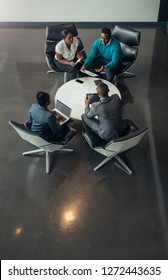 Group Of North African Business People Sitting And Discussing Statistics During A Sit Down Meeting Taking From Above