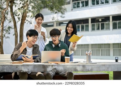 Group off cheerful young Asian college students looking at laptop screen, rejoicing, and celebrating their school project success or exam score together at a campus park. - Powered by Shutterstock