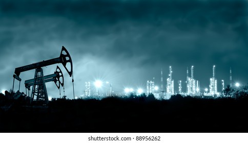 Group Oil Rigs And Brightly Lit Industrial Site At Night. Toned.