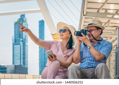 group of old asian traveler or senior tourist couple enjoy travel on city tour in town by city guide on smartphone