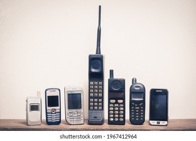 Group of old and obsolete mobile phone or cell phone on old wood with a light rough background