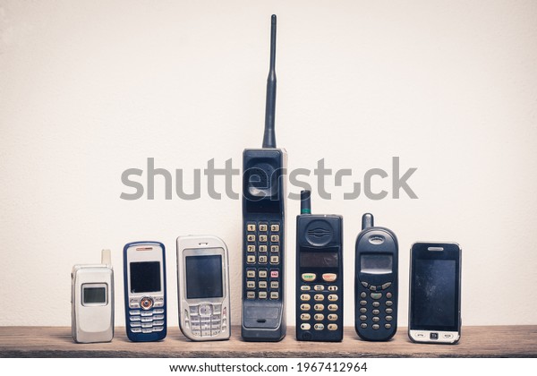 Group of old and obsolete mobile\
phone or cell phone on old wood with a light rough\
background