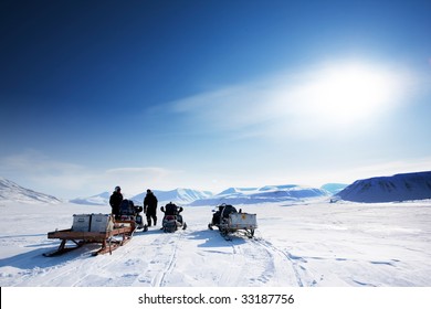 A Group On A Winter Snowmobile Adventure Over A Barren Winter Landscape