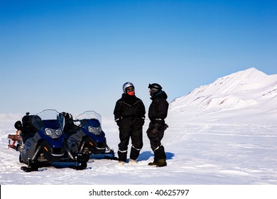 A Group On A Winter Snowmobile Adventure Over A Barren Winter Landscape