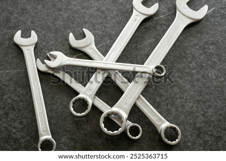 Group of open end and ring spanners  in different sizs are lying on dark table in loose order..