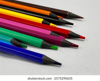 A group of overlapping colored pencils are shown in the image. There are nine pencils with a variety of colors such as blue, green, red, pink, yellow, orange, and brown.