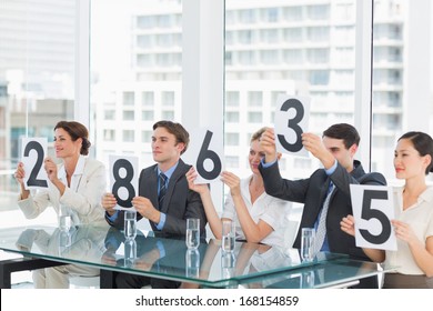 Group Of Panel Judges In A Row Holding Score Signs