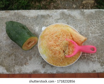 Group Of Papaya Cut Into Strips And Pink Scraper In White Plate On Cement Bench