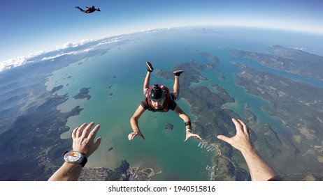 A group of parachuting friends jumping over the sea. First person view.