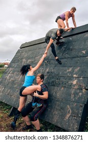 Group of participants in an obstacle course climbing a pyramid obstacle