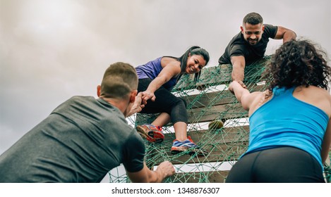 Group of participants in an obstacle course climbing a net - Shutterstock ID 1348876307