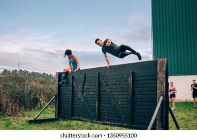 Group of participants in an obstacle course climbing a wall - Powered by Shutterstock